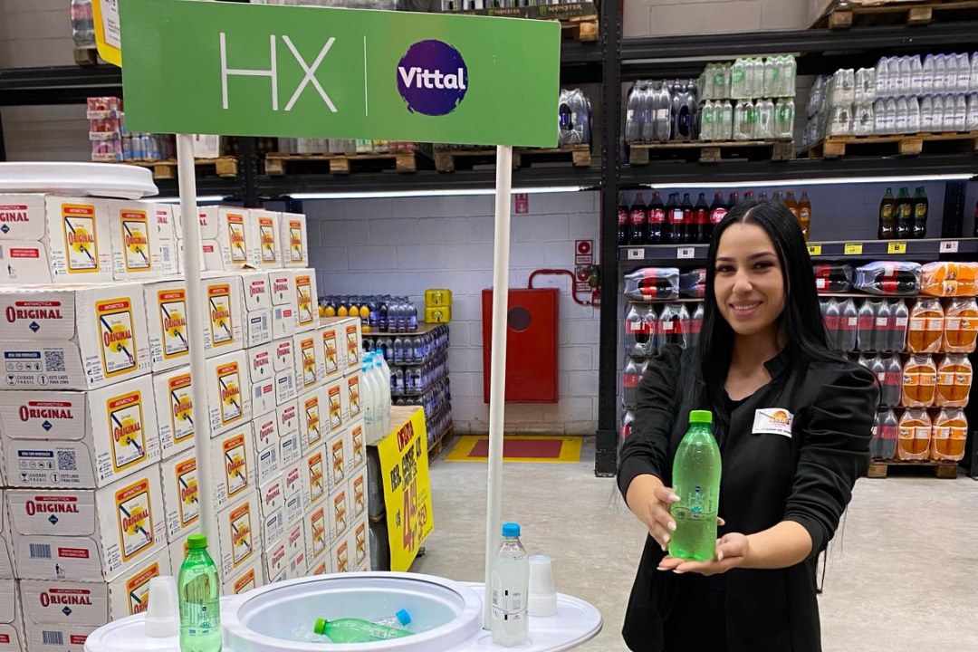 Promotora da HAVC registrando atendimento ao lado de exposicao em loja de atacarejo