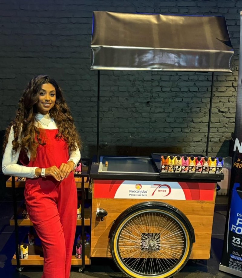 Promotora da HAVC ao lado de carrinho promocional da Piracanjuba em ação de evento